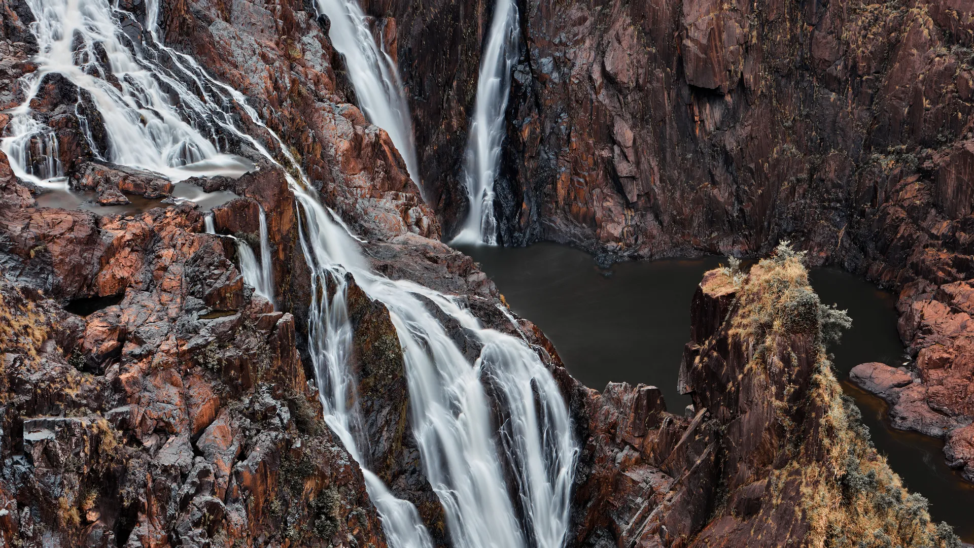 Cascading waterfall flowing over dark red rock formations, Kuranda National Park, Queensland, Australia