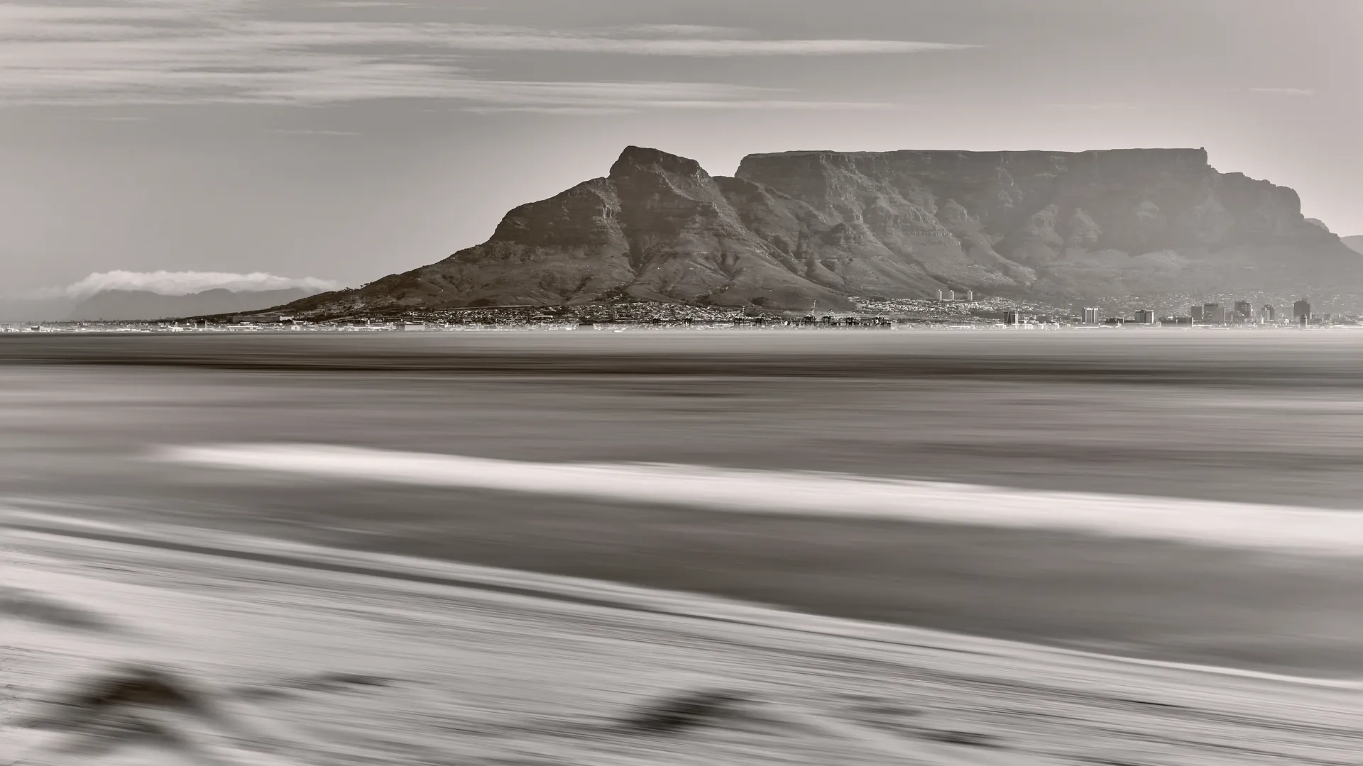 Long exposure black and white seascape of Table Mountain viewed across the bay in Cape Town, South Africa