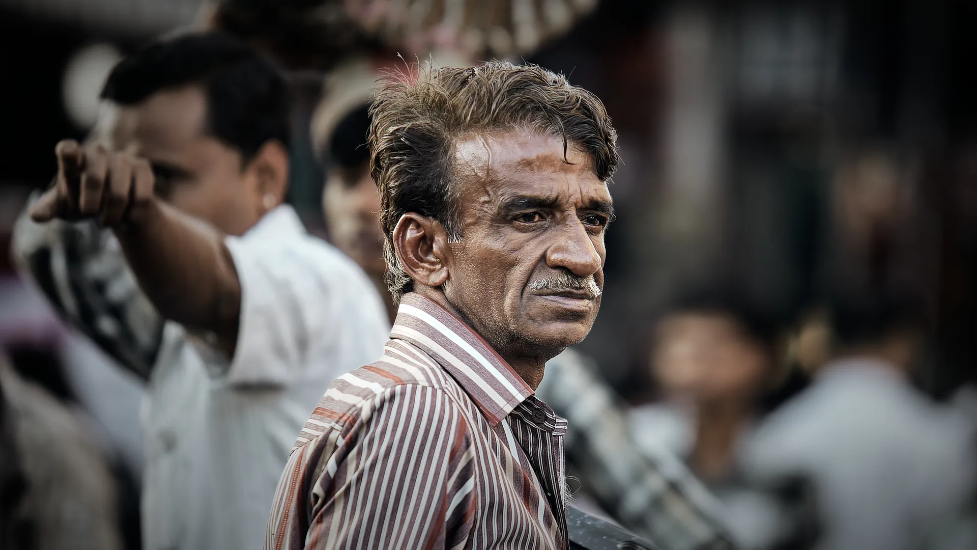 Street portrait of a man in a striped shirt with a weathered face in India