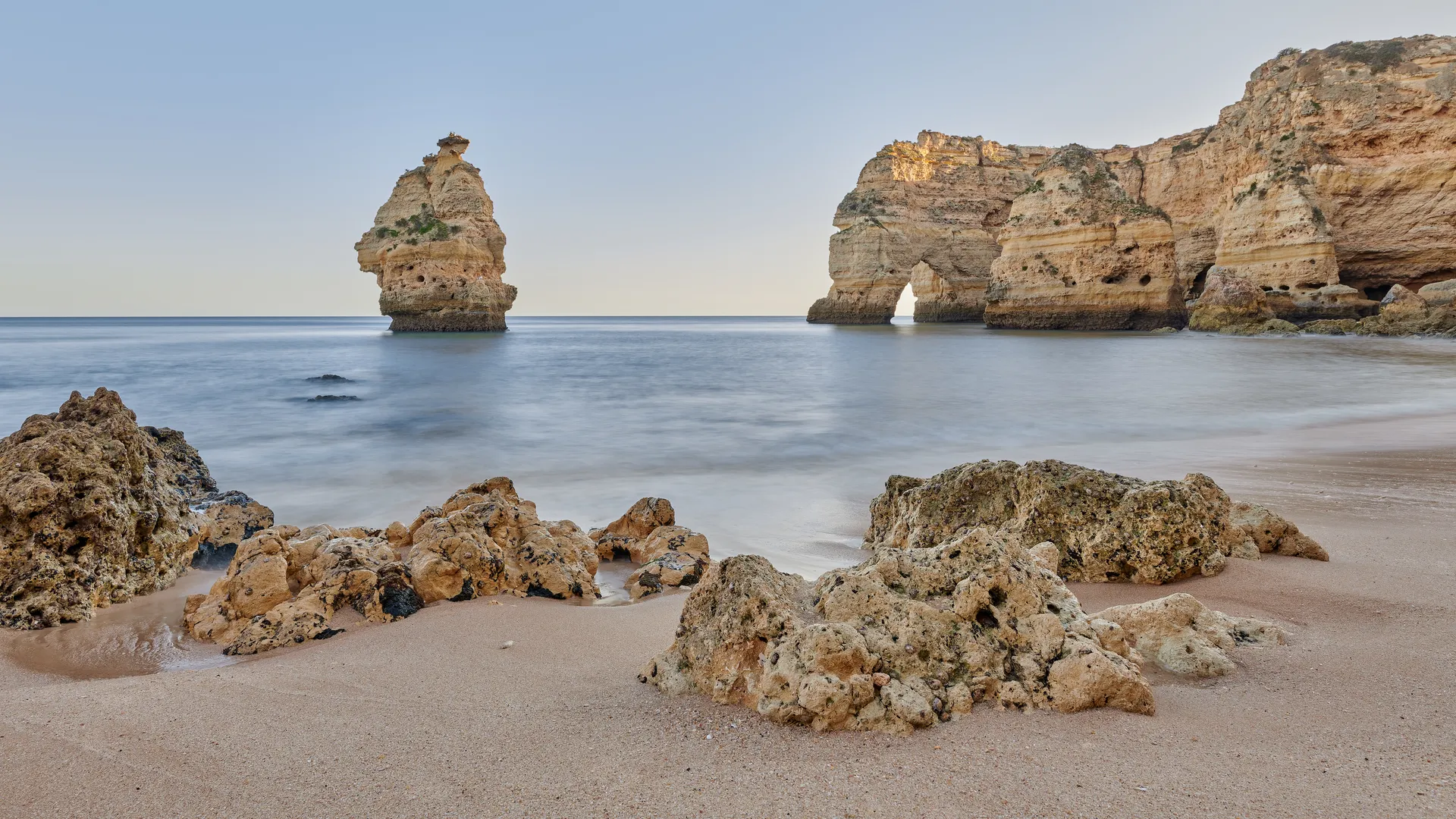 Golden limestone sea stacks and rock formations on an Algarve beach at dusk