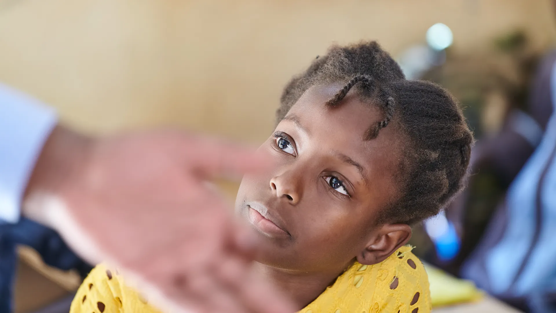 Portrait of a young African child in a yellow top with a gentle smile, Somone, Senegal