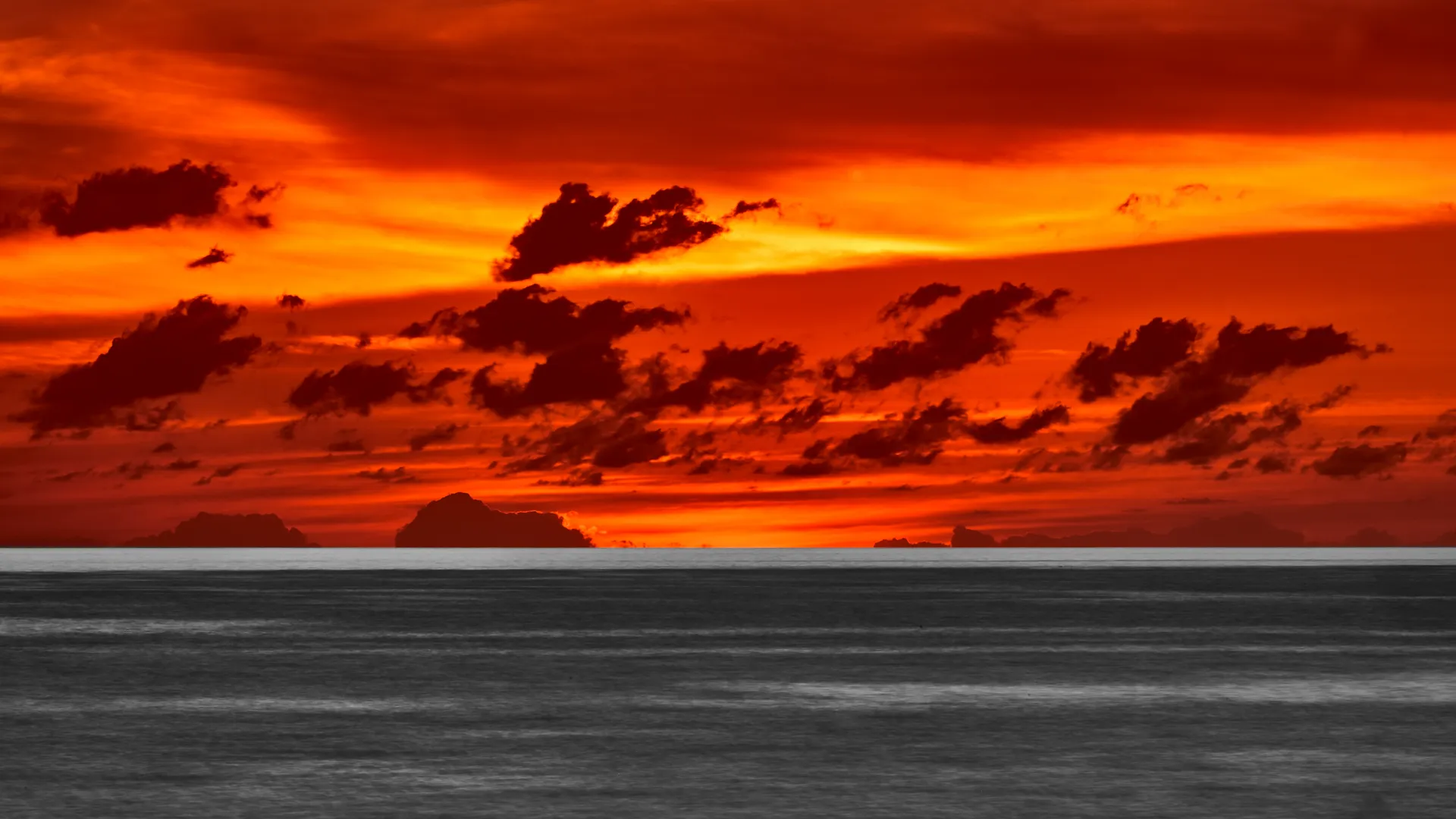 Dramatic fiery orange sunset over a calm ocean with distant islands on the horizon, Guadeloupe Island, France, Carribeans